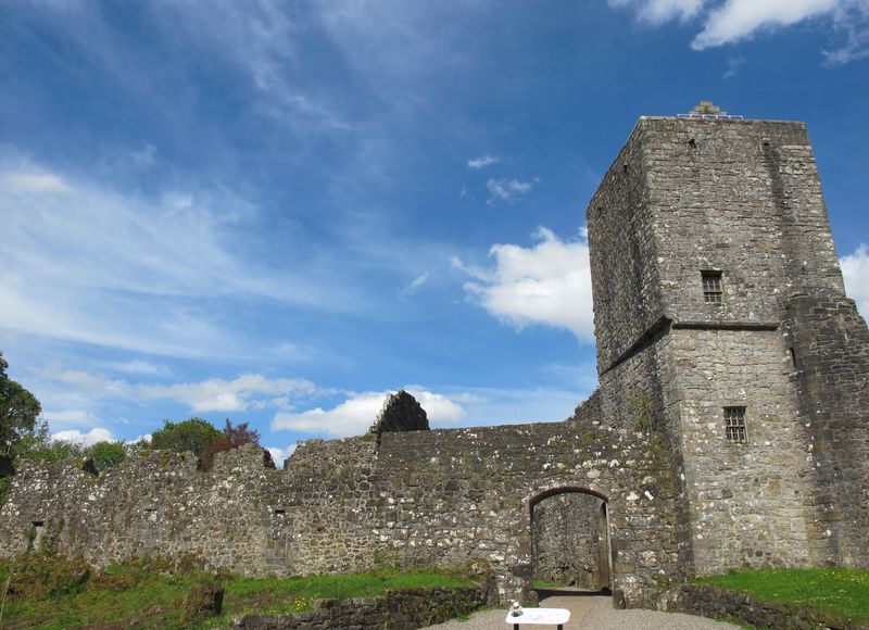 The stone tower and curtain wall of Mugdock Castle under a blue sky