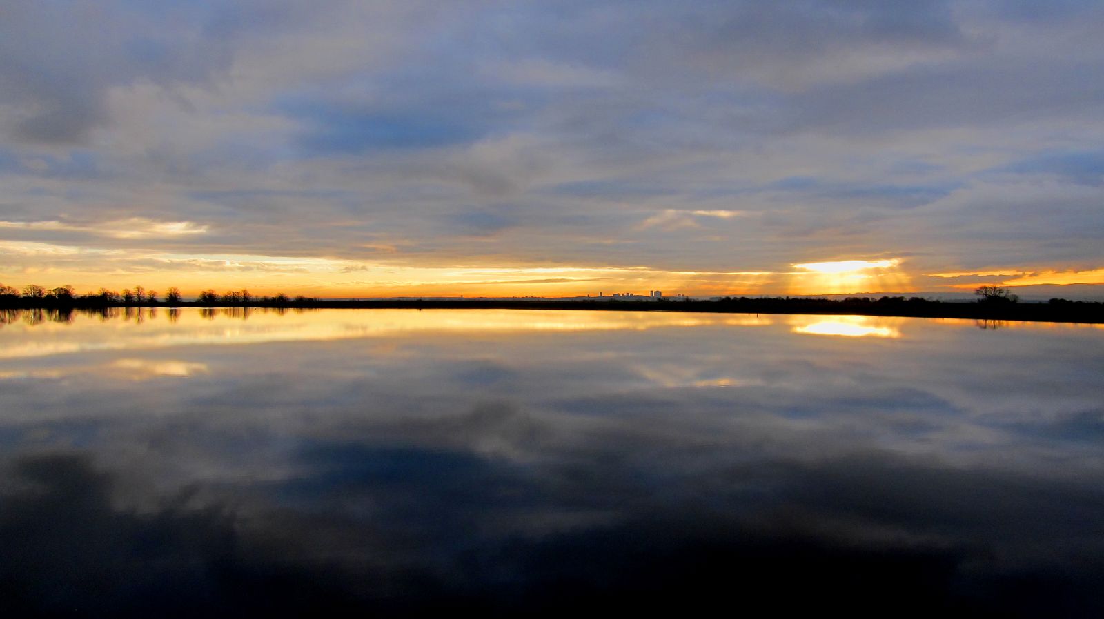 Mugdock Reservoir at dusk, the sky gold above still water